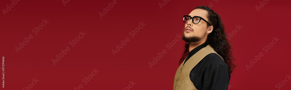 Fototapeta premium Handsome young bearded man in stylish attire against a vibrant red backdrop during a trendy event