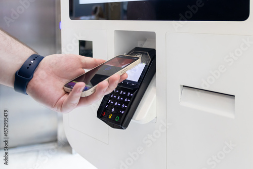 Obraz na plátně Hand using smartphone for Card Payment at a self-service terminal, highlighting
