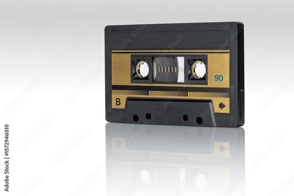Fototapeta premium Retro magnetic audio cassette with golden label reflected on glossy white surface