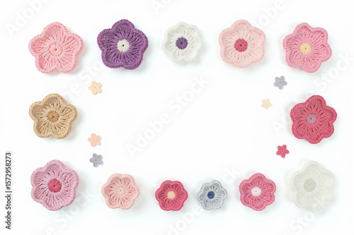 Flat lay of various crochet flowers in different shapes and pastel colors, arranged on a white background with copy space inside