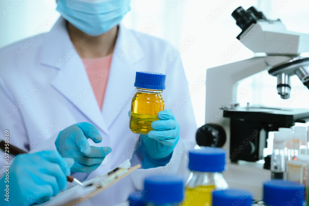 Fototapeta premium Scientists in lab coats and gloves pour blue liquid from one test tube to another to perform chemical experiments in a laboratory environment.
