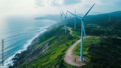 Coastal wind turbines on a lush green hillside overlooking a vast ocean, capturing clean energy