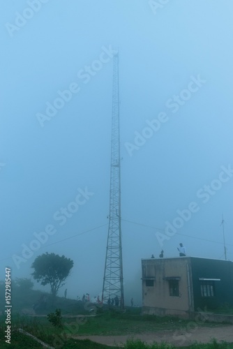 Misty morning at Nandi Hills, Karnataka, India. A tall communication tower dominates the hazy landscape.