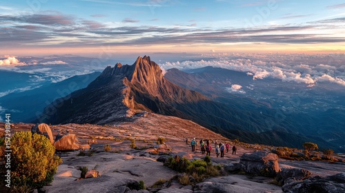 Hikers on Mountain Summit with Jagged Peak and Cloudy Sky