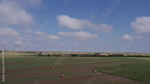 Aerial shot of hay bales in field in Kansas with sky and clouds