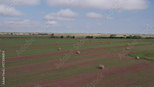 Aerial shot of hay bales in field in Kansas with sky and clouds