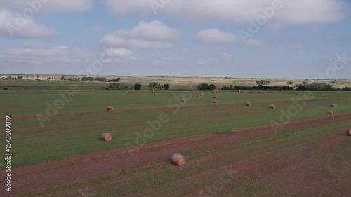 Aerial shot of hay bales in field in Kansas with sky and clouds