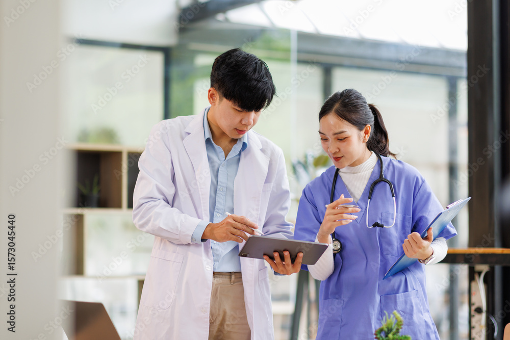 Obraz premium A Female nurse showing something on tablet to Male doctor both smiling in hospital 