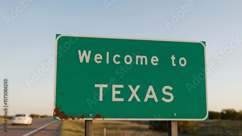 Rustic green sign welcoming travelers to texas on a quiet rural highway at sunset