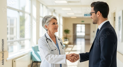 Mature woman doctor shaking hands with pharmaceutical representative at hospital
