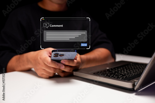 A person holding a smartphone near a laptop, with a digital comment box overlay indicating online communication or social media interaction.