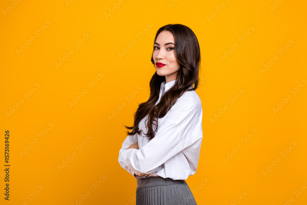 Confident young woman in a white shirt posed against a vibrant yellow backdrop, showcasing elegant style and grace Confident young woman in a white shirt posed against a vibrant yellow backdrop, showcasing elegant style and grace