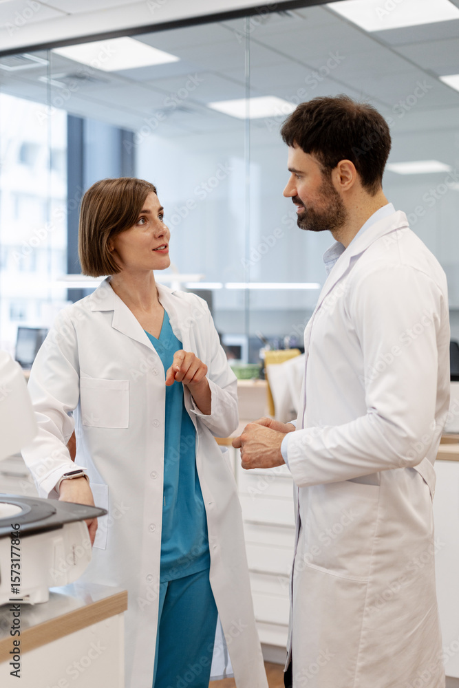 Fototapeta premium Medical professionals discussing near laboratory equipment in modern clinic