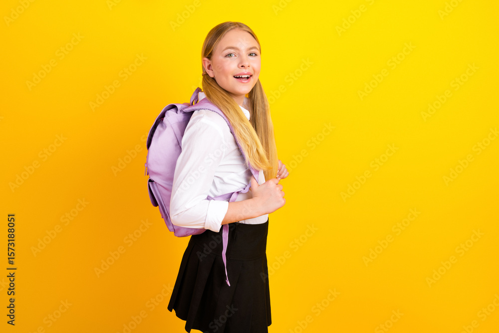 Happy young schoolgirl with a lavender backpack smiling confidently against a vibrant yellow background showcasing enthusiasm for learning Happy young schoolgirl with a lavender backpack smiling confidently against a vibrant yellow background showcasing enthusiasm for learning