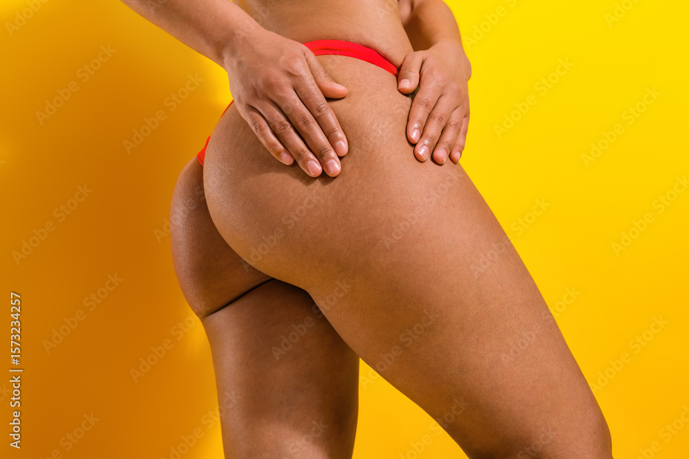 Attractive woman in red swimsuit posing against a vibrant yellow background, showcasing confidence and natural beauty Attractive woman in red swimsuit posing against a vibrant yellow background, showcasing confidence and natural beauty