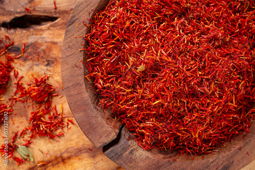 Fototapeta Naklejka Na Ścianę i Meble -  Spice saffron threads, in a wooden bowl, on a wooden table, top view, close-up,