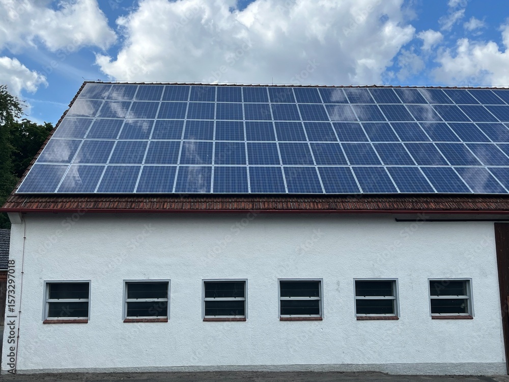 Fototapeta premium Solar cells on an old roof, blue sky with white clouds in the background, concept: renewable energies