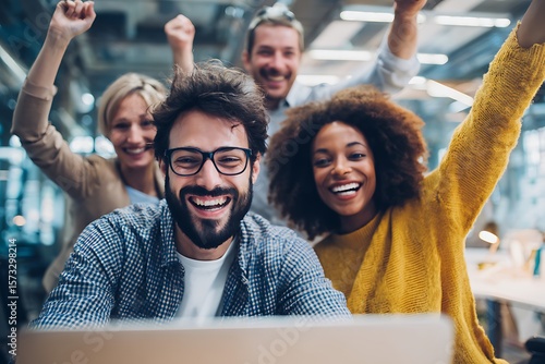 group of young people cheering while watching at laptop