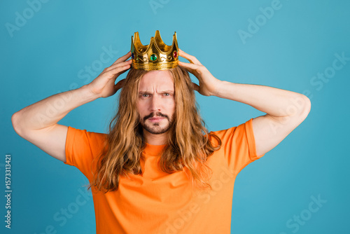 Obraz na plátně Young man with long blond hair wearing a golden crown poses in a bright orange s
