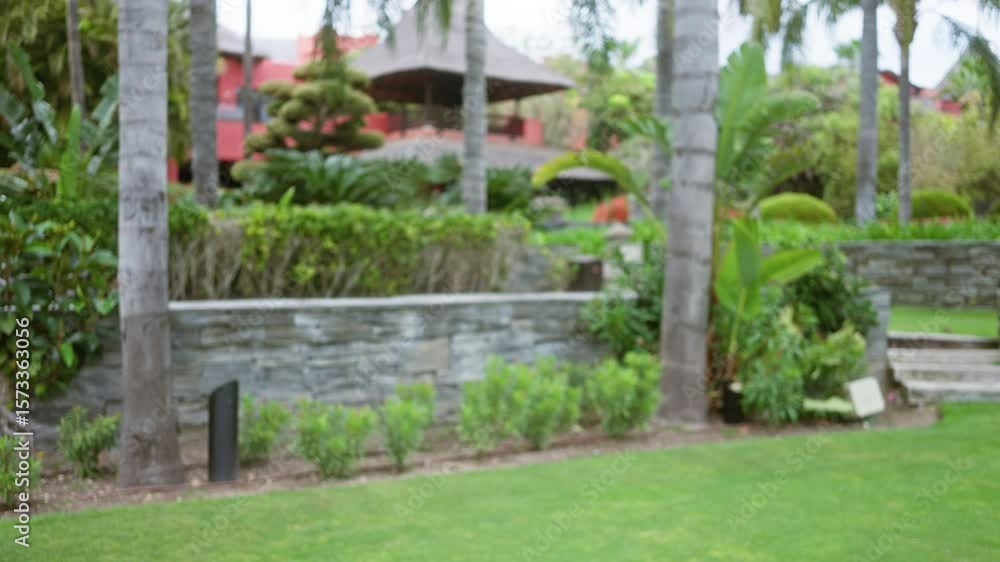 Defocused view of a lush, tropical resort showcasing vibrant greenery and palm trees surrounding a luxury outdoor setting, creating a serene bokeh ambiance. Defocused view of a lush, tropical resort showcasing vibrant greenery and palm trees surrounding a luxury outdoor setting, creating a serene bokeh ambiance.