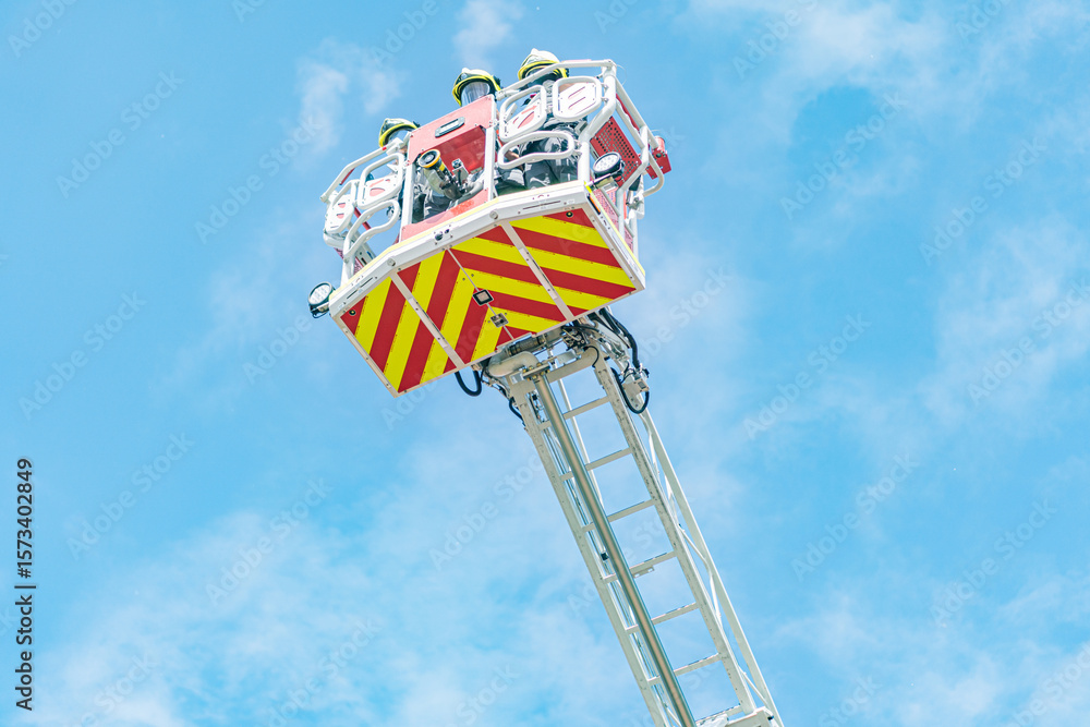 Fototapeta premium Rescue operation with fire truck ladder and two firefighters, daytime scene with clear sky