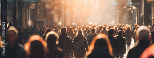 Busy crowd walking along city street in warm autumn sunlight   -