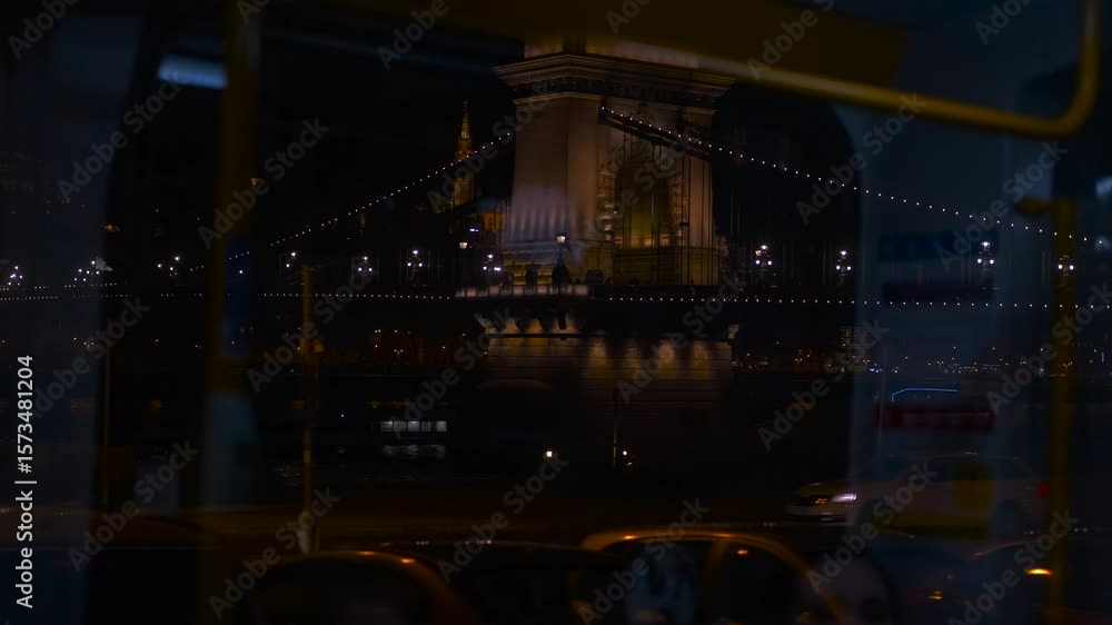 Nighttime cityscape revealing budapest's illuminated chain bridge through public transport window, capturing urban journey and architectural landmark reflecting city lights Nighttime cityscape revealing budapest's illuminated chain bridge through public transport window, capturing urban journey and architectural landmark reflecting city lights