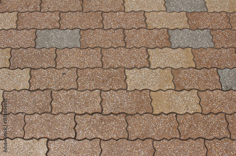 Obraz premium Texture of paving tile. Pattern of gray, brown, and beige sidewalk tiles in the street. Concrete pavers close up background. 