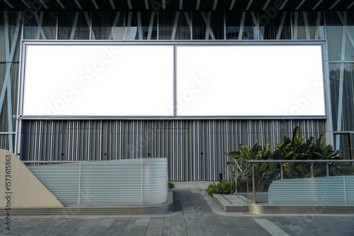 Mockups of two blank white billboards framed by a modern building facade, ideal for advertising
