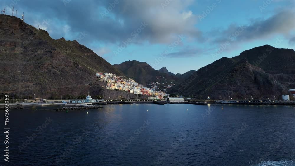 Wide shot of San Andrés village on the coast of Tenerife. Vibrant houses climb the mountain slope near the sea, framed by rugged Anaga peaks and soft sunset light. Wide shot of San Andrés village on the coast of Tenerife. Vibrant houses climb the mountain slope near the sea, framed by rugged Anaga peaks and soft sunset light.