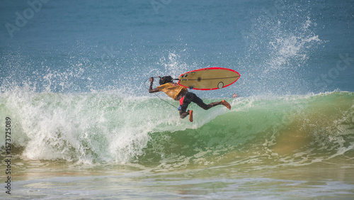 Surfer wipes out mid-air during a failed trick, with the surfboard flying alongside him above the crashing wave. Unpredictable, high-risk nature of surfing