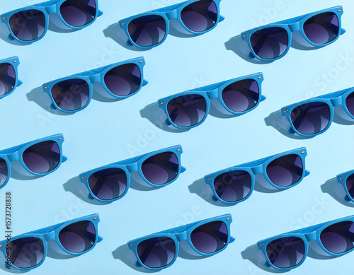 A repeating pattern of blue sunglasses casts shadows on a light blue background.