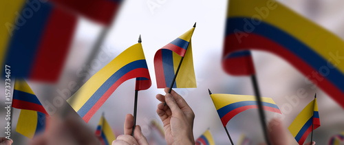 Colombia flags in their hands on a blurred urban background
