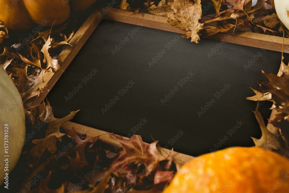 Fototapeta premium Black screen surrounded by brown leaf and pumpkin