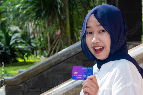 Quadro em tela Cheerful Asian Muslim girl showing credit card with mouth gaping
