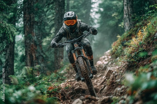 A mountain biker wearing full gear rides through a dense forest on a rocky trail, showcasing intense focus and skill in an adventurous outdoor setting.