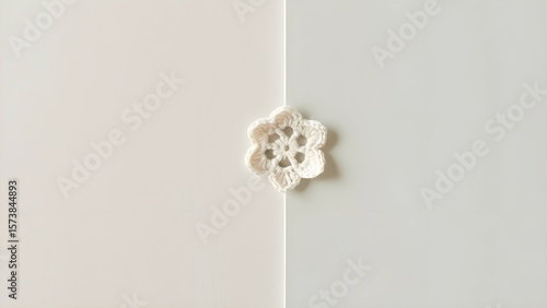 A simple and minimalist background with a small crocheted flower in the middle of the image. 