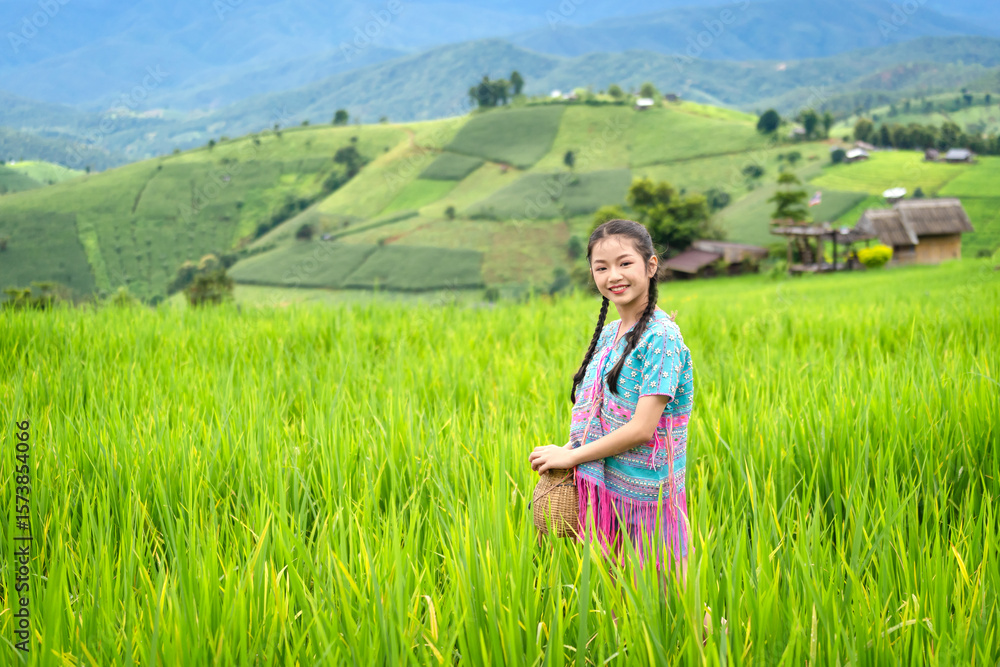 Pretty teenage travellers wearing custom-made Karen dresses in a natural green terraced rice fields at Pa Bong Piang rice fields, Mae Chaem, Doi Inthanon, Chiang Mai, Thailand. Pretty teenage travellers wearing custom-made Karen dresses in a natural green terraced rice fields at Pa Bong Piang rice fields, Mae Chaem, Doi Inthanon, Chiang Mai, Thailand.