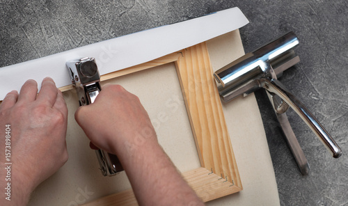 The process of stretching the canvas onto the stretcher frame.