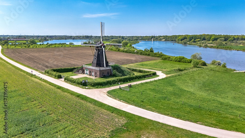 Aerial drone view of typical Dutch countryside landscape with traditional old windmill, fields and river Meuse in spring, the Netherlands