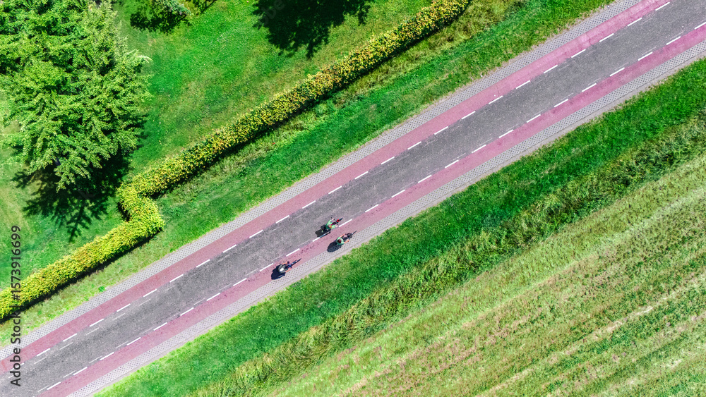 Fototapeta premium Group of people cycling on bicycle lane aerial drone view from above, beautiful cycling path, typical Dutch countryside landscape and cyclists on bikes in the Netherlands
