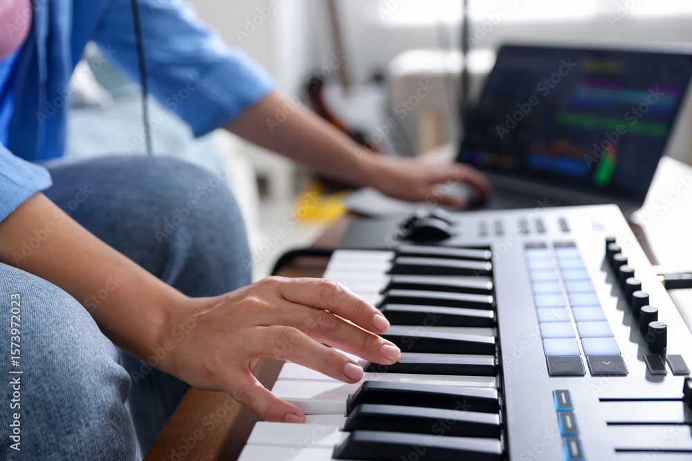 Obraz premium Woman working with MIDI keyboard and laptop at table indoors, selective focus