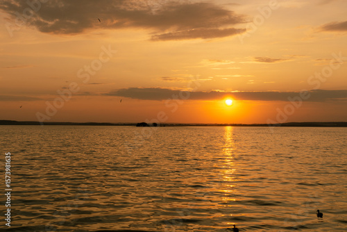 Golden sunset over calm water with reflections and gentle waves
