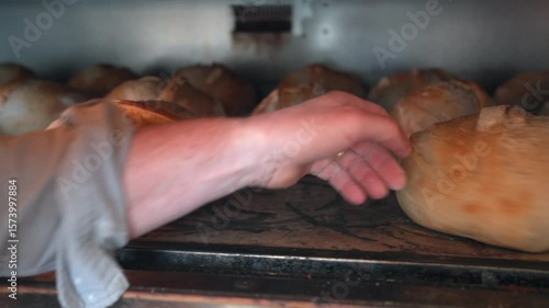 Close Up Of Male Baker Checking On Sourdough Loaves In Bakery Oven