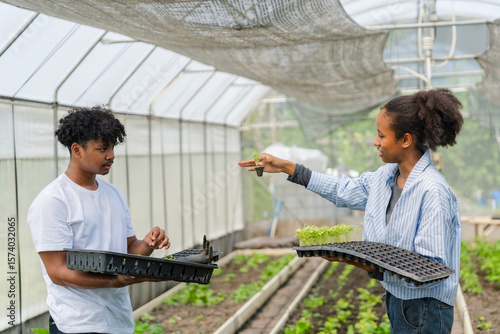 Group of young people working together in a greenhouse, growing and caring for green vegetables. Diverse team of farmers or students engaged in sustainable agriculture.