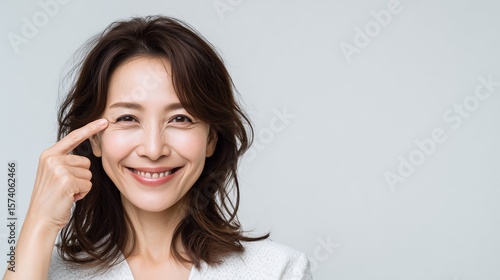 目尻のしわを指さす女性