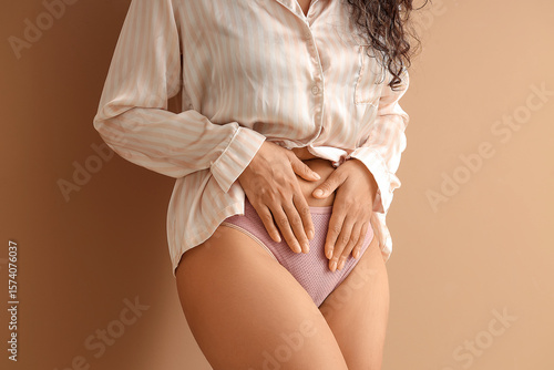 Fotografie Young woman in menstrual panties on brown background, closeup