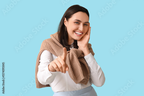 Smiling young woman pointin...