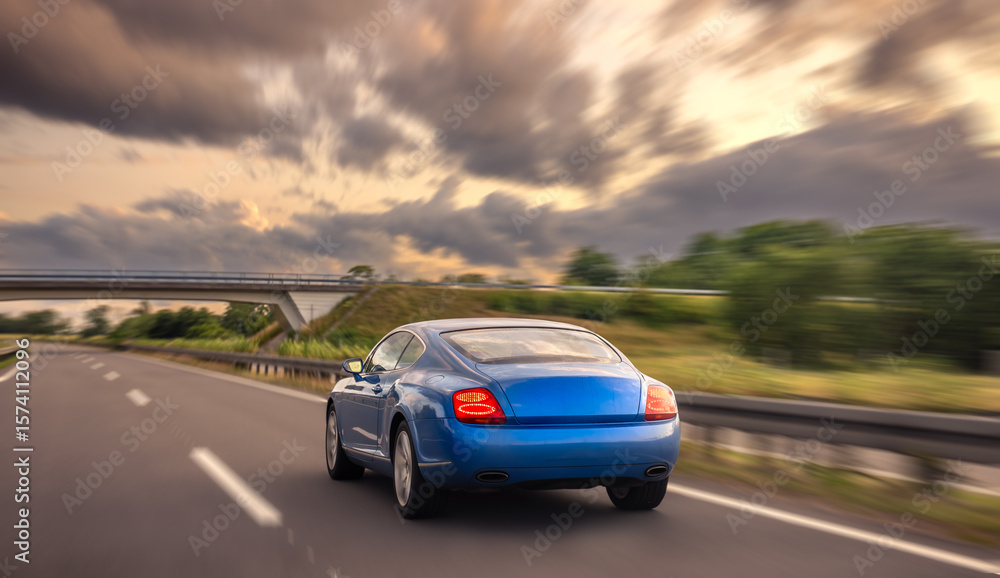 Fototapeta premium Speeding car on highway. Blue coupe. Motion blur at sunset.