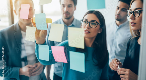 Team brainstorming, using colorful sticky notes on glass wall, showcasing collaborative teamwork and planning process, ideal for business or project management concepts